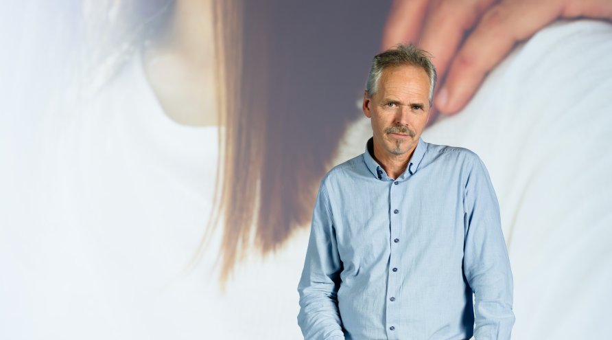 Portrettbilde av Pål Iden, direktør i Ukom. Han står foran skjem som viser utsnitt av rapport.