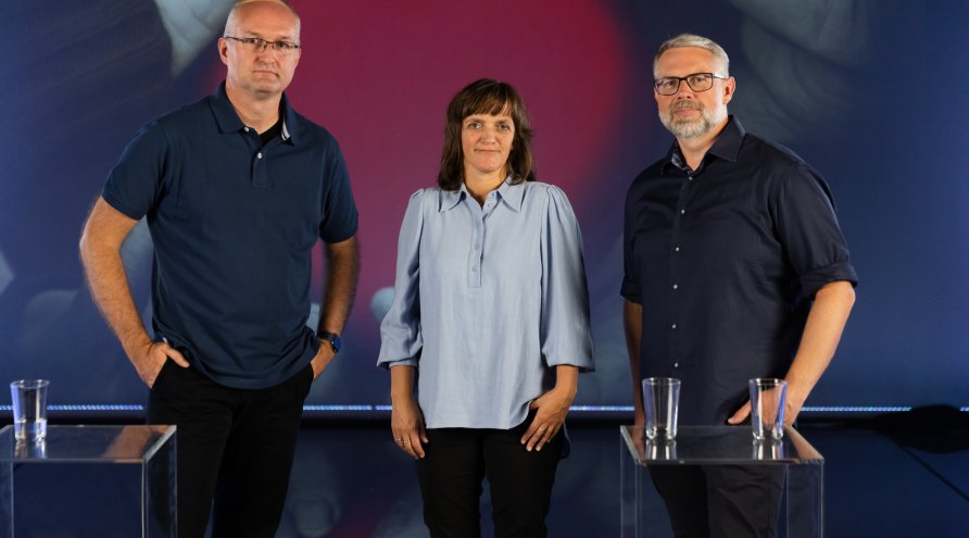 Tre personer som står sammen i studiosetting-