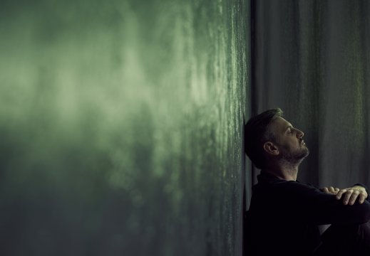 Mann lener hodet inntil en vegg