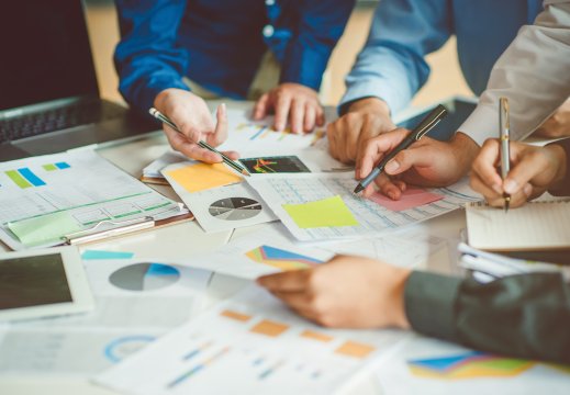 Mennesker som team jobbe sammen, hender holder blyanter og peker på papir som ligger på bordet, utsnittet er av armer og hender.